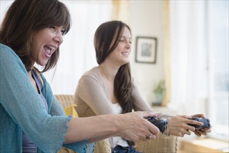 Teenage girl (14-15) playing video games with her mom