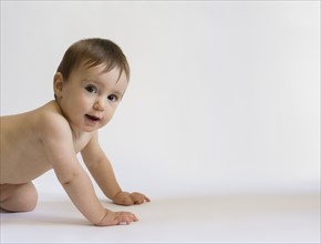 Portrait of baby girl (12-17 months) crawling on white background