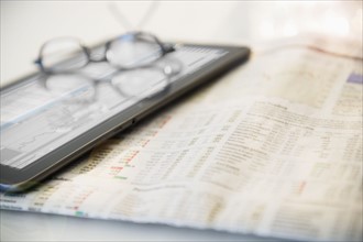 Newspaper, eyeglasses and digital tablet
