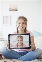 Girl (12-13) holding tablet with selfie