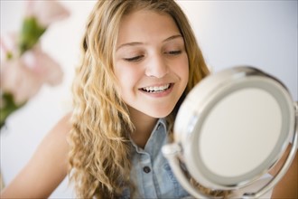 Girl (12-13) smiling to mirror