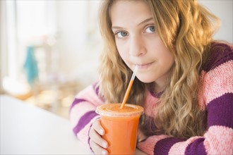 Girl (12-13) sipping carrot juice