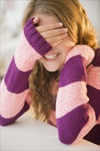 Girl (12-13) grinning and covering eyes