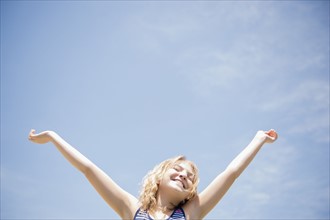 Girl (12-13) with arms raised, smiling