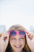 Girl (12-13) with pink sunglasses