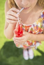 Girl (12-13) drinking soda from bottle using straw