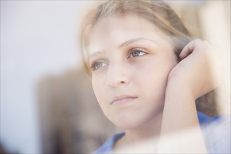 Portrait of teenage girl (12-13) looking through window