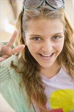 Portrait of smiling teenage girl (12-13) showing peace sign