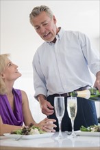 Portrait of man pouring champagne at restaurant table