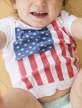 Studio shot of little girl (18-23 months) in t-shirt with American flag