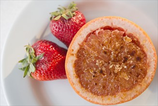 Studio shot of grapefruit with caramelized sugar and strawberries