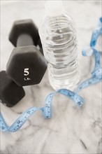 Studio shot of water bottle, measuring tape and weights