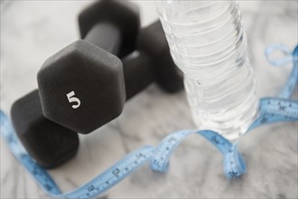 Studio shot of water bottle, measuring tape and weights