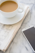 Studio shot of coffee cup, newspaper and smart phone