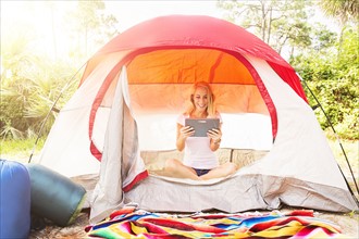 Woman sitting with digital tablet in tent