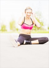 Young woman listening to music while stretching
