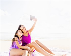 Mom taking picture with her daughter (6-7) on beach