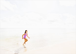 Girl (6-7) running on beach