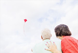 Low-angle view of couple flying kite together