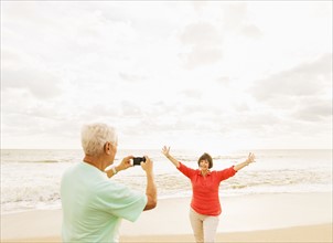 Couple taking pictures on beach at sunrise