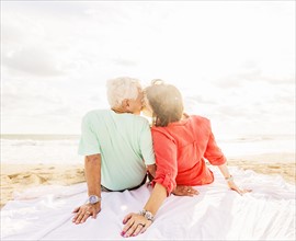 Rear view of couple kissing on beach at sunrise
