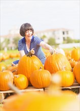 Mature woman picking up pumpkins