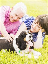 Smiling couple with dog lying in grass
