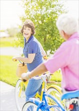 Portrait of woman looking over shoulder at senior man, while getting on bicycle and laughing