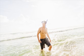 Portrait of young man walking in surf wearing scuba mask and snorkel