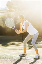 Portrait of young woman playing tennis in outdoor court
