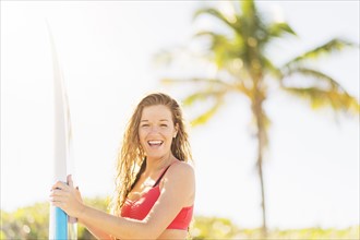 Portrait of young woman holding surfboard on beach