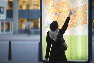 Young woman pointing at city map