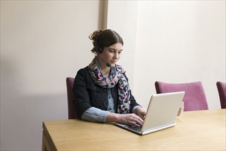 Woman wearing headset working on laptop