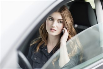 Young woman speaking on phone in car