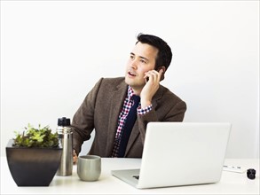 Businessman sitting in office and making phone call
