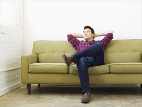 Man sitting on sofa with crossed legs and head in hands