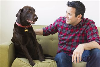 Man and Chocolate Labrador sitting on sofa