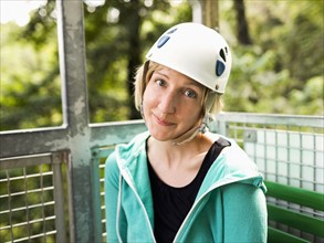 Woman in protective helmet and sitting at net elevator looking at camera