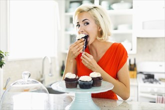 Woman eating muffins at kitchen