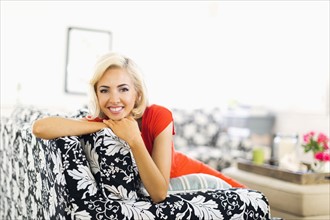 Woman lying down on sofa and smiling to camera