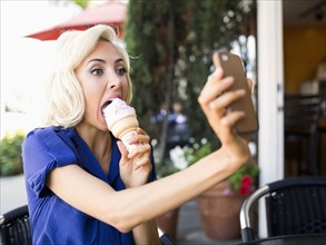 Woman photographing herself with ice-cream