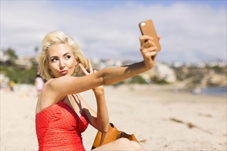 Blond woman taking selfie on beach