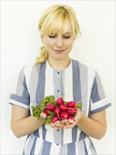 Studio shot of woman holding bunch of fresh radishes