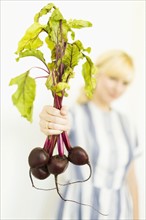 Studio shot of woman holding bunch of beetroots