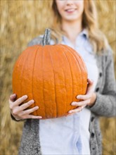 Woman holding huge pumpkin in pumpkin patch