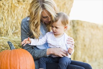 Mother and daughter (12-17 months) looking at large pumpkin