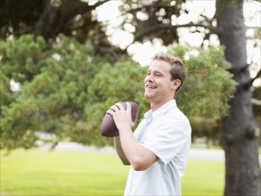 Portrait of young man playing football in park
