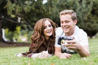 Portrait of young couple taking selfie in park