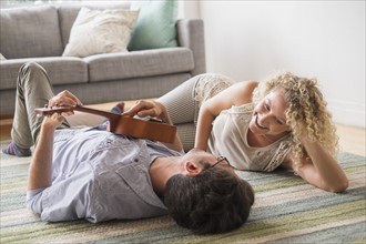 Couple lying on floor playing ukulele.