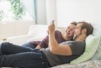 Smiling couple lying on bed and using digital tablet.